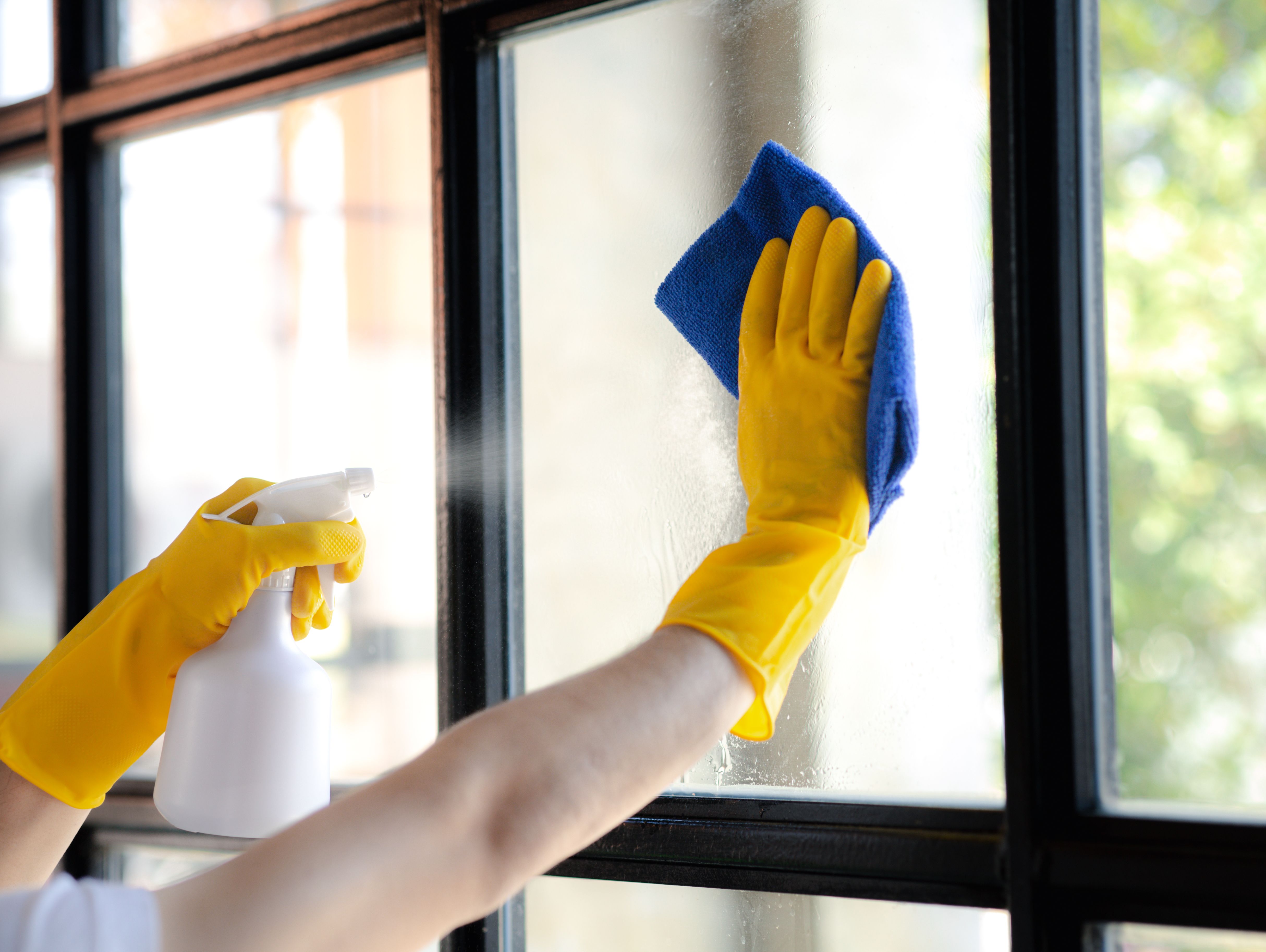 Person som torkar ett fönster med duk